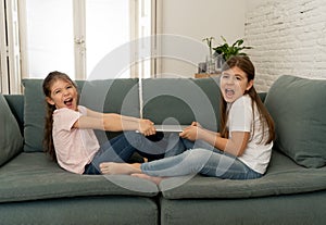 Two sisters fighting for laptop computer. Children and technology addiction