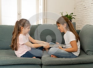 Two sisters fighting for laptop computer. Children and technology addiction