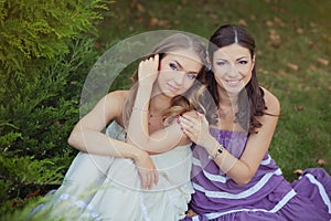 Two sisters friends blond brunette blue eyes lady girls posing together summer sunny day evening dressed in white purple airy dinn