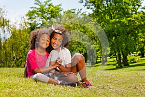 Two sisters hold hands sitting in the park lawn