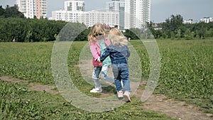 Two sisters holding hands circling on the lawn in the city park outdoors. Freedom and carefree concept