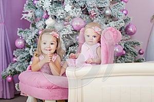 Two sisters at home with Christmas tree. Portrait of happy children girls decorations.