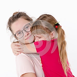 Two sisters hugging, Studio portrait on white background
