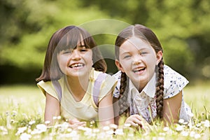 Two sisters lying outdoors smiling