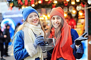 The two sisters met at the Christmas market. Women are drinking coffee on the street and chatting