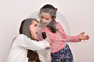 Two sisters with a microphone fooling around and singing