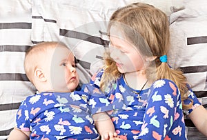 Two sisters. Older sister kid hugging his newborn little sister.