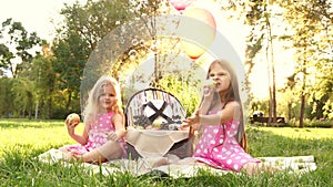 Two sisters at picnic blow bubbles.