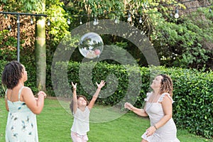 Two sisters playing a ball game with their mother in the park