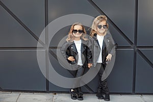 Two sisters in same outfits: white t-shirts, leather black jackets and leggings, sunglasses hearts.