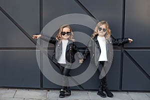 Two sisters in same outfits: white t-shirts, leather black jackets and leggings, sunglasses hearts.