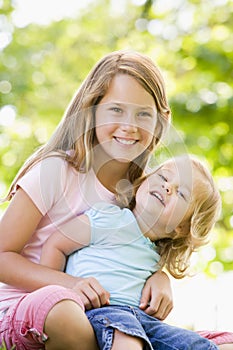 Two sisters sitting outdoors smiling