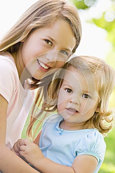 Two sisters sitting outdoors smiling