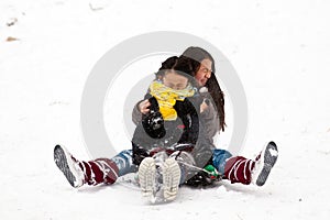 Two sisters sledging holding each other