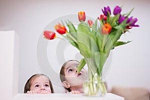 Two sisters with spring tulip bouquet. Holiday decor with flowers colorful tulips