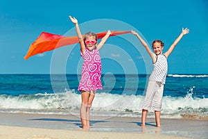 Two sisters standing on the beach and pulled up his hands