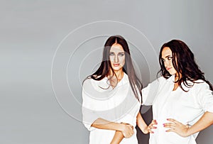 Two sisters twins posing, making photo selfie, dressed same whit