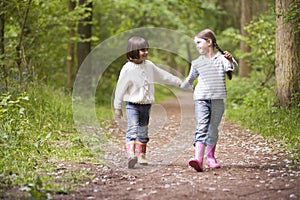 Two sisters walking on path holding hands smiling