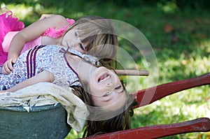 Two sisters on wheelbarrow