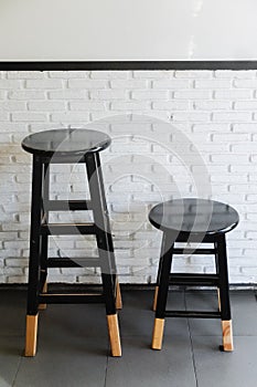 Two size black wooden stool in front of brick wall