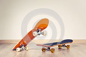 Two skateboards yellow and red on a wooden floor background