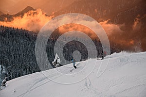 Two skiers descend slope against the backdrop of winter mountain scenery