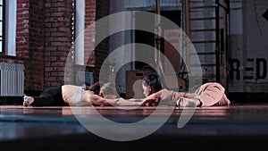 Two skinny women training together in the gym - doing stretching exercises in front of each other - sitting in splits