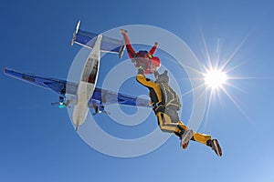 Two skydivers in color suits have just jumped out of an airplane.