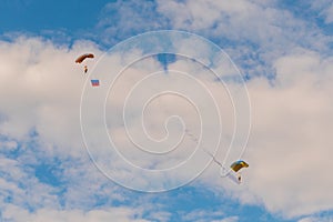 Two skydivers flying with parachute against blue sky - extreme sport concept