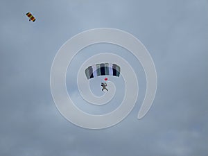 Two skydivers in the sky with colorful parachutes on a blue sky background