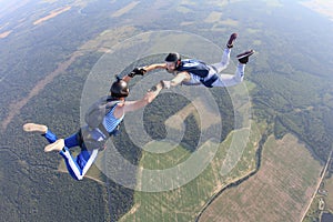 Two skydivers in striped T-shirts are flying in the sky.