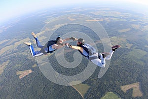 Two skydivers in striped T-shirts are flying in the sky.