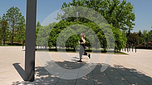 Two slender young women run through a modern park in summer. Sport.