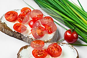 Two sliced bread, butter, cherry tomato, chive. On white background, closeup.