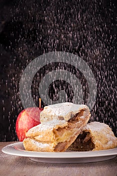 Two slices of apple strudel with spilled sugar