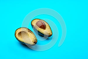 Two slices of avocado isolated on the blue background. One slice with core