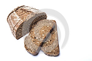 Two slices of black whole grain farm bread with a loaf of bread on a white background