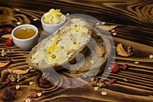 Two slices of bread and a cup of honey and butter and decorated with pieces of dried apple lying on a wooden background