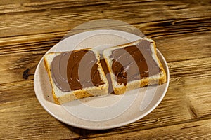 Two slices of bread with delicious chocolate hazelnut spread on wooden table