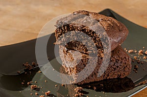 Two slices of chocolate brownies on a black plate on wooden table