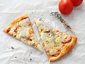 Two slices of freshly made pepperoni pizza upon baking parchment. Food background.