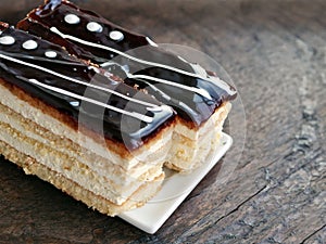 Two slices of layered cake with butter cream and chocolate icing on wooden table