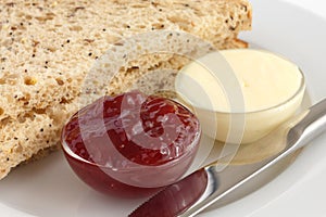 Two slices of multigrain bread with jam and butter