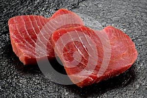 Two Slices of raw tuna fillet on polished black stone