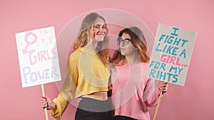 Two slim feminists isolated over pink background