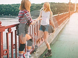 Two slim and young women and roller skates. One female has an inline skates and the other has a quad skates. Girls