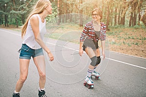 Two slim and young women and roller skates. One female has an inline skates and the other has a quad skates. Girls