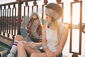 Two slim and young women and roller skates. One female has an inline skates and the other has a quad skates. Girls