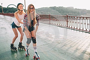 Two slim and young women and roller skates. One female has an inline skates and the other has a quad skates. Girls