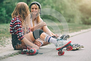 Two slim and young women and roller skates. One female has an inline skates and the other has a quad skates. Girls